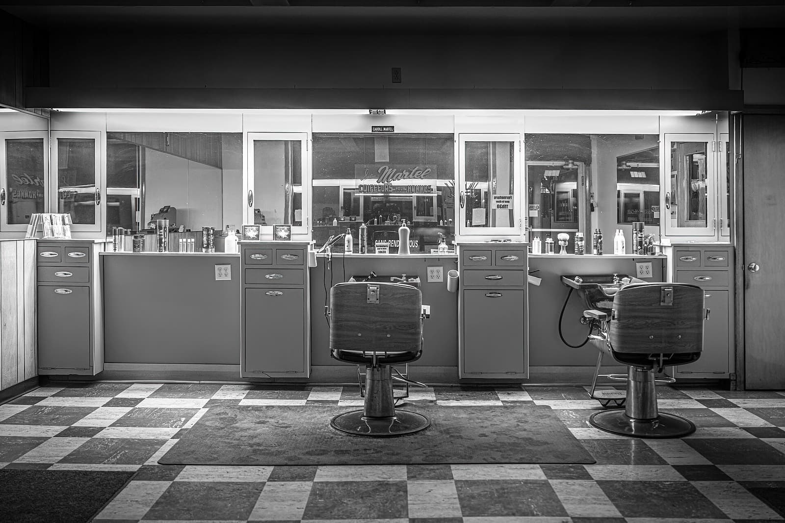 Barbearia em preto e branco com cadeiras e bancada de espelhos