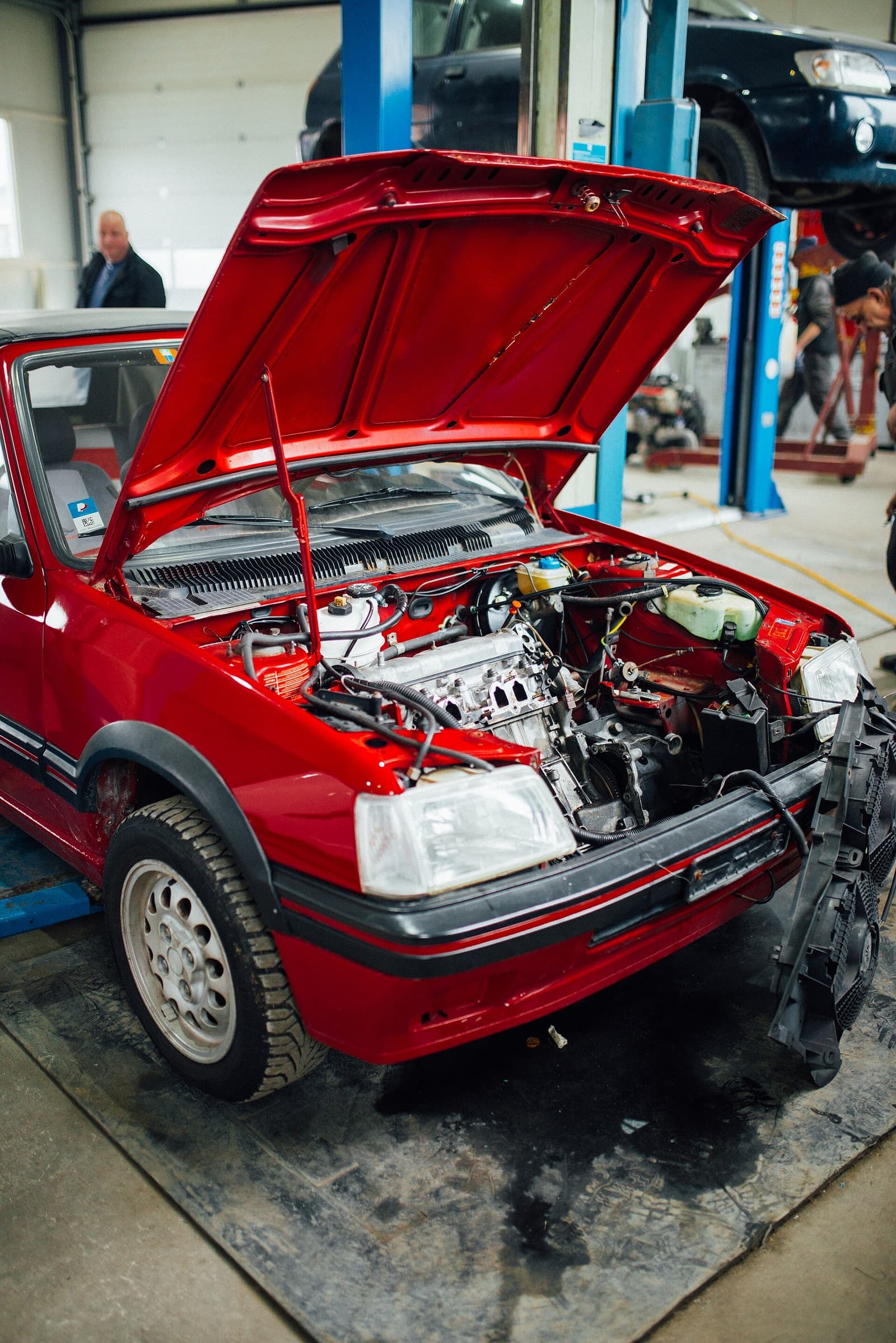 Carro vermelho com o capô aberto em oficina